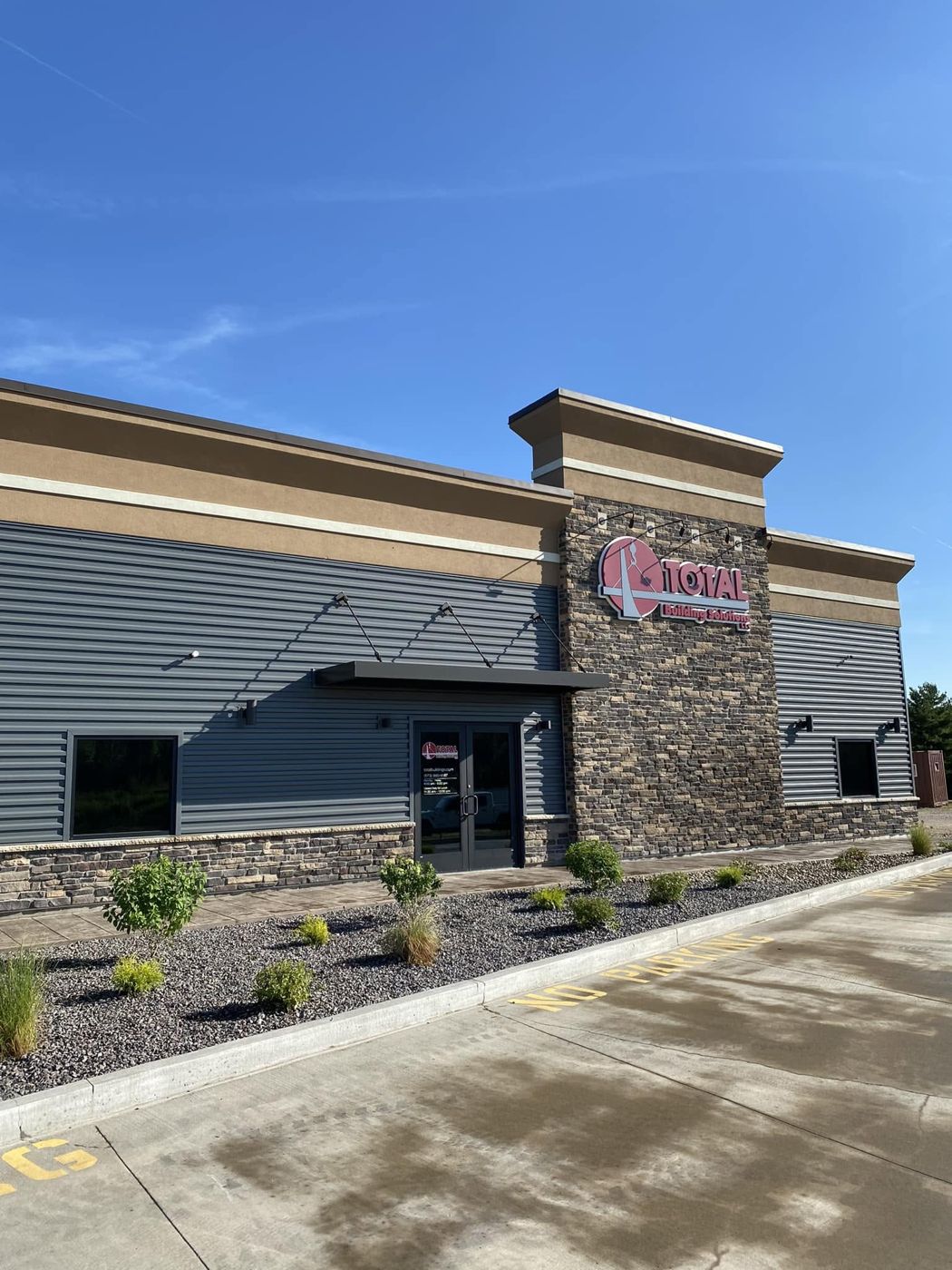 The Total Building Solutions office in Bourbon: grey metal wall panels, a stone tower and the TOTAL sign